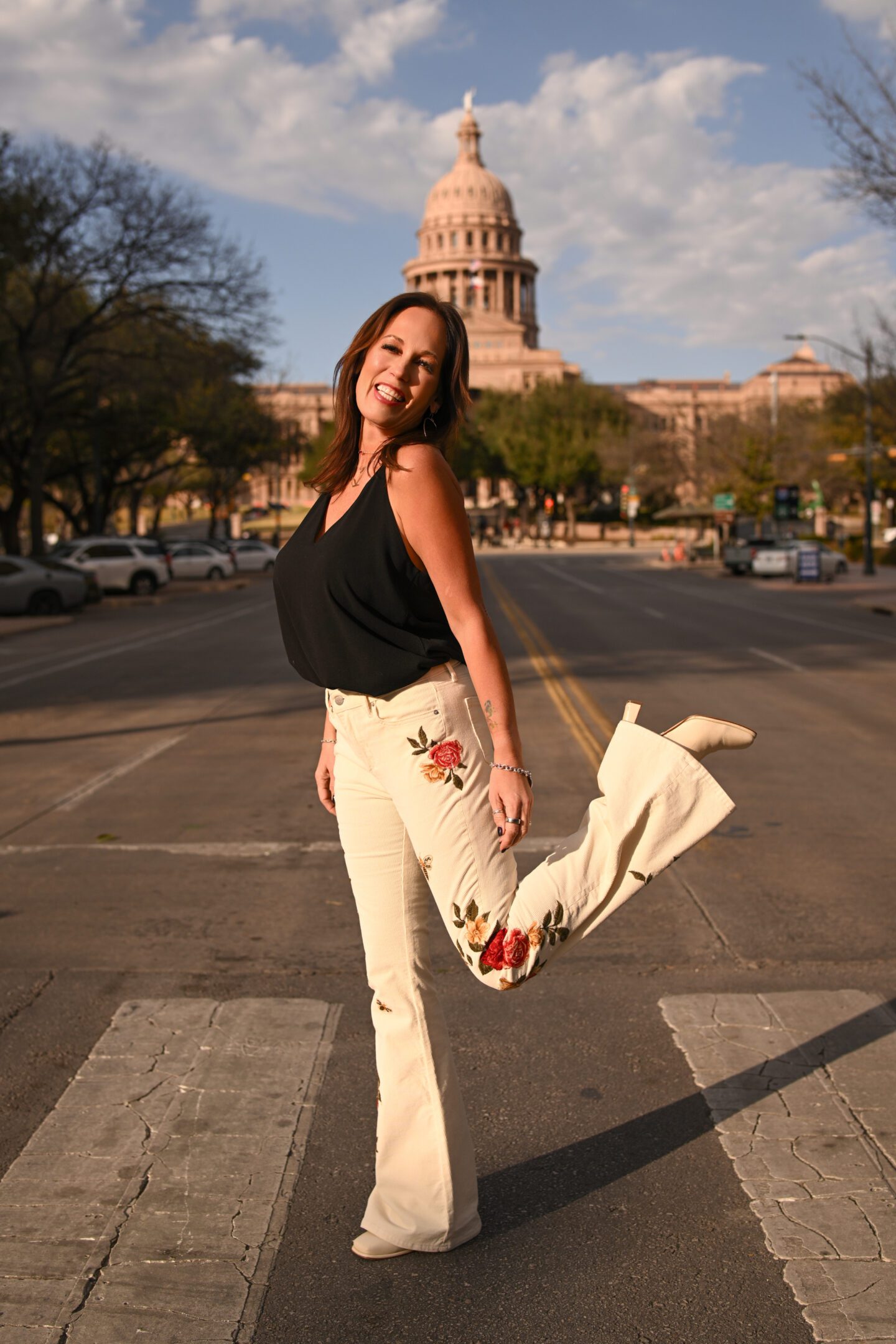 Woman posing joyfully on a city street at sunset.